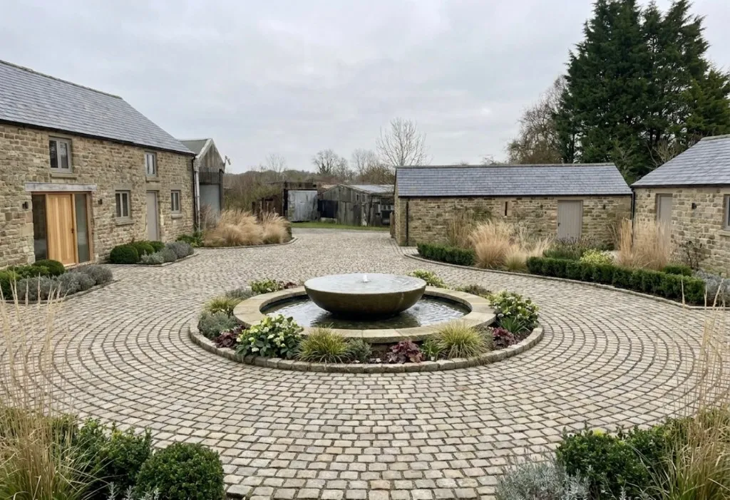 Landscaped cobbled courtyard with planting around a circular driveway